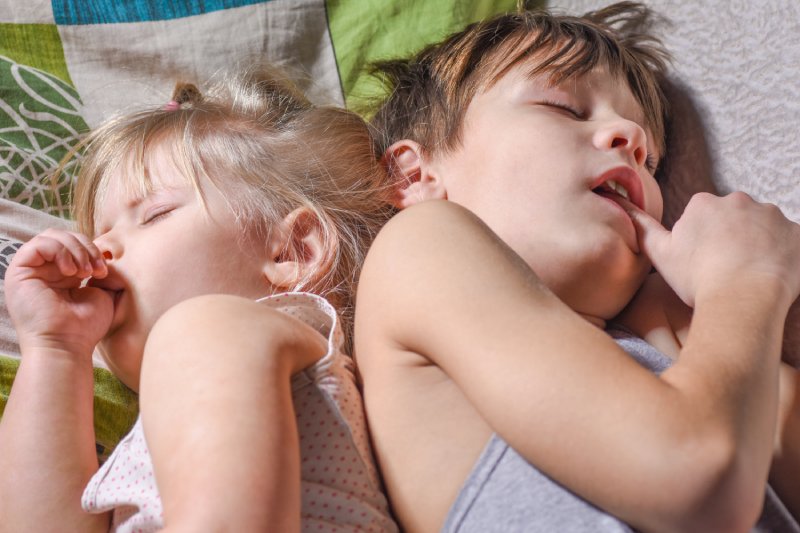 Broer en zus slapen en doen aan duim- of vingerzuigen in bed